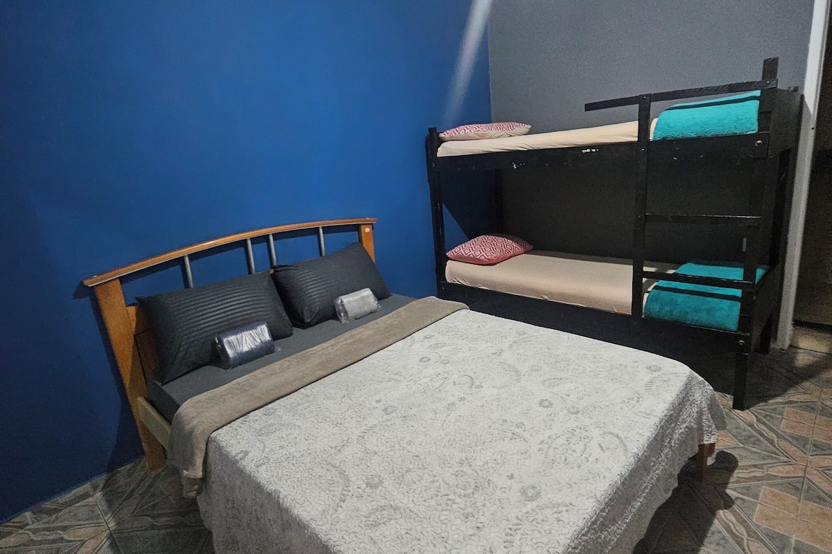 A room with a single bed, a bunk bed, blue walls, and patterned floor tiles.