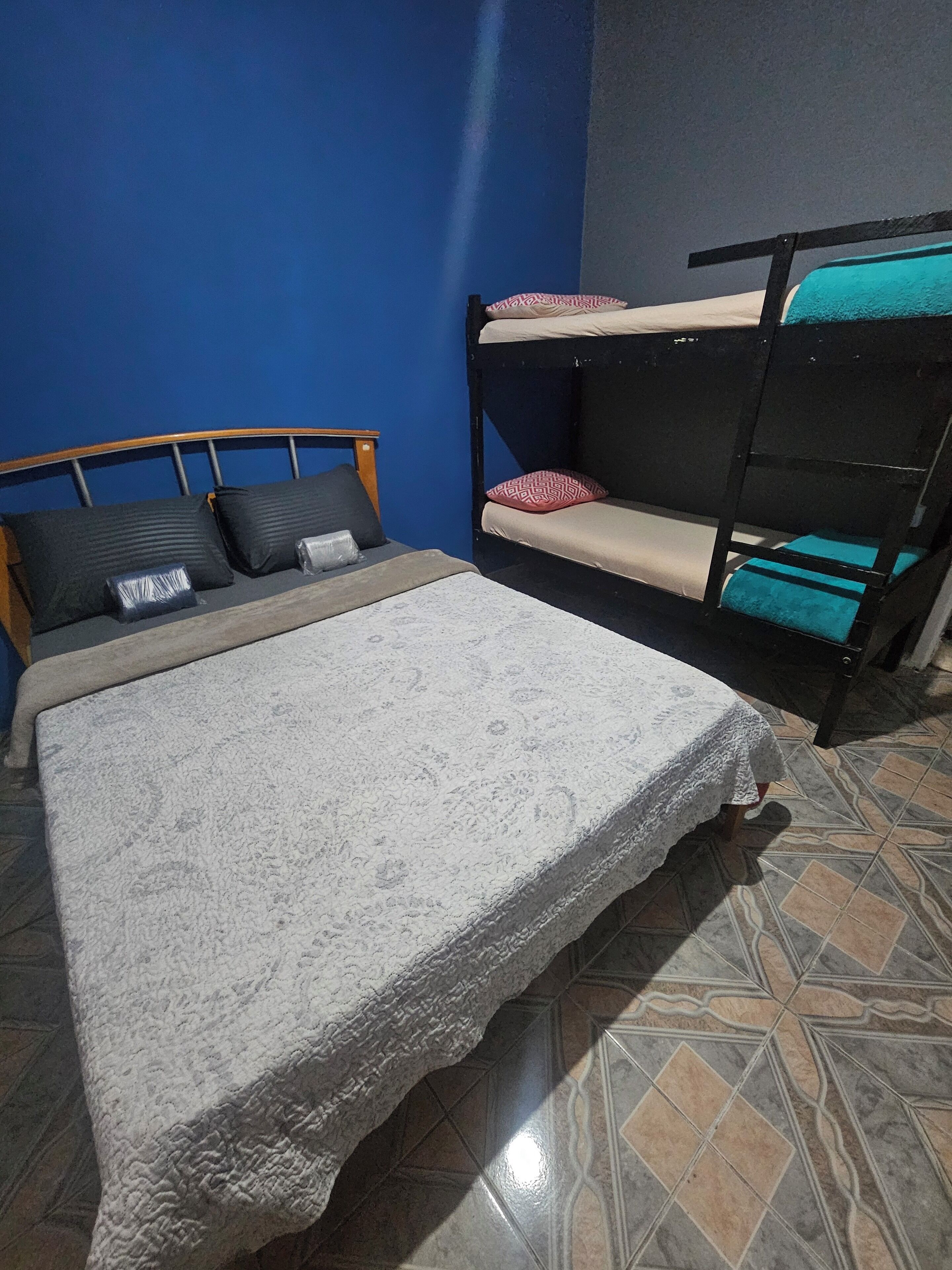 A room with a bunk bed, a single bed, and a patterned bedspread.