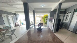 A spacious indoor area with a polished granite counter, several chairs, and a small table. - Hope Hostel (Guarapari)