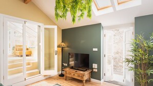 Una sala de estar con un televisor sobre una mesa de madera, una lámpara y una planta verde.
