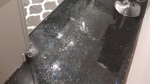 Una cocina con encimera negra, electrodomésticos de acero inoxidable y alfombra estampada.