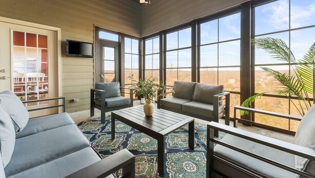 A sunroom with a ceiling fan, large windows, and a view of the desert. - Perfect for Family Reunions & Large Groups! 3 Pools - Games - Golf - Firepit! (Branson West)