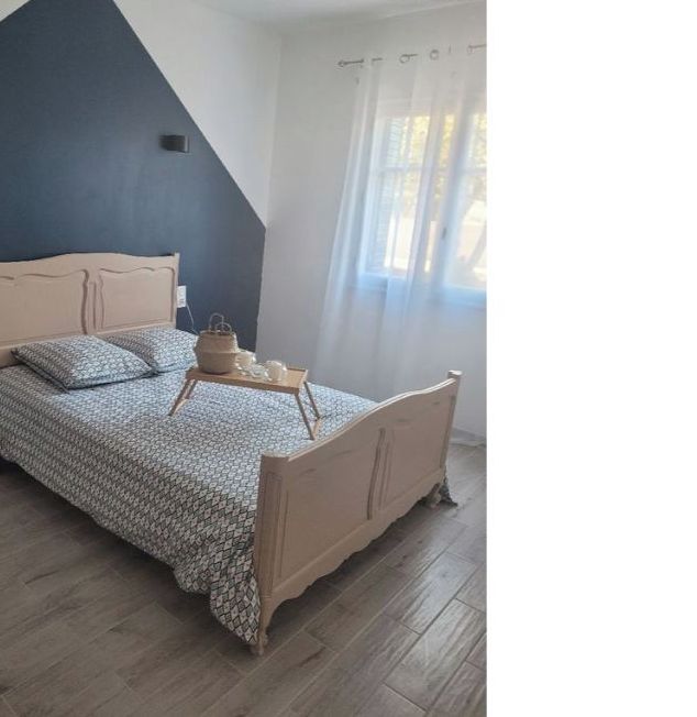 Una camera da letto con un letto, un comodino e una finestra con tende.