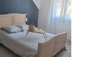 Una camera da letto con un letto, un comodino e una finestra con tende.