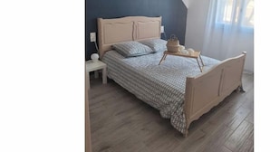 A bedroom with a bed, bedside table, and a window with curtains.