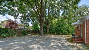 A gravel driveway leading to a house with a brick exterior and a porch. - Duke East Campus 2BR Buchanan (Durham)