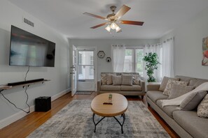 A living room with a ceiling fan, a flat-screen TV, a sofa, a coffee table, and a potted plant. - Duke East Campus 2BR Buchanan (Durham)