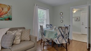 A dining area with a table set for four, a sofa with patterned cushions, and a painting on the wall. - Duke East Campus 2BR Buchanan (Durham)