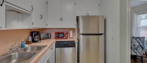 A compact kitchen with white cabinets, stainless steel appliances, a dishwasher, and a microwave.