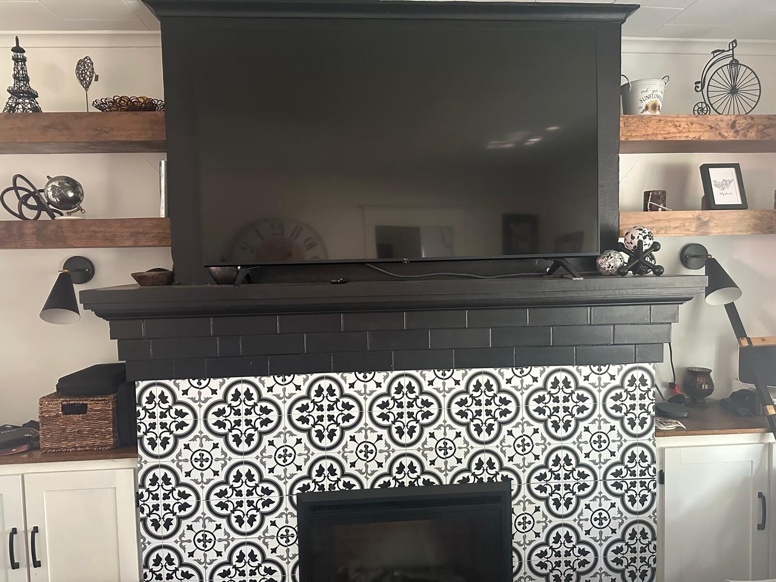 Una chimenea con un televisor encima, rodeada de estantes con objetos decorativos.