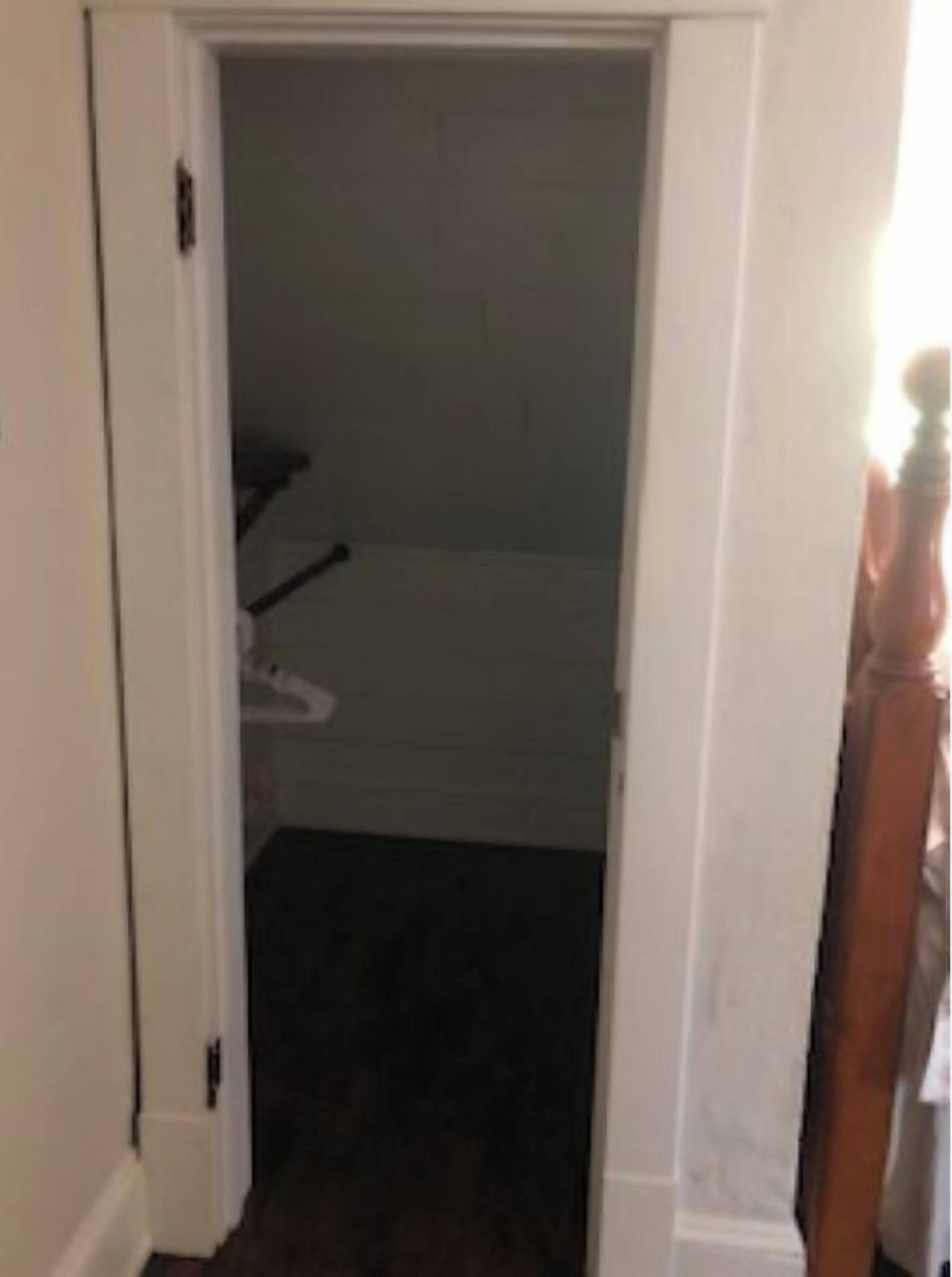 Un pasillo estrecho con un marco de madera y una puerta blanca.