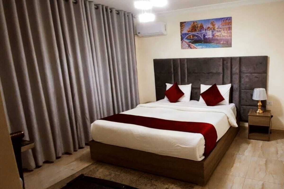 A hotel room with a large bed, a nightstand with a lamp, and a painting on the wall.
