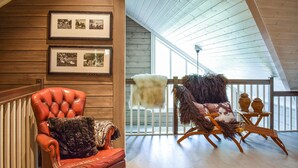 A room with a wooden ceiling, a red leather chair with a fur throw, and a wooden rocking chair with a fur throw. - Lovely home in Vossestrand with WiFi (Vossestrand)