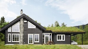A black wooden house with a stone chimney, white windows, and a covered porch. - Lovely home in Vossestrand with WiFi (Vossestrand)