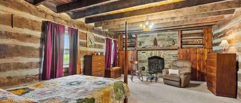 Un dormitorio tipo cabaña con edredón acolchado, muebles de madera y chimenea de piedra.