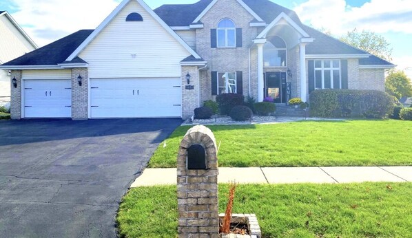 A two-story house with a garage, a stone mailbox, and a well-maintained lawn. - Entire lower level in a private home with walkout fenced yard. (Freeport)