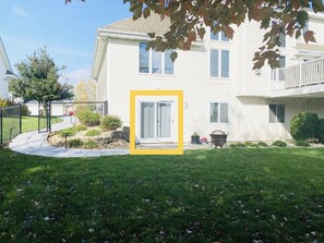 A two-story house with a front yard, a fenced driveway, and a small garden area. - Entire lower level in a private home with walkout fenced yard. (Freeport)