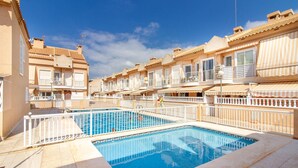 A swimming pool surrounded by multi-story buildings with balconies and outdoor seating areas. - Beach front home in Santa Pola (Santa Pola)