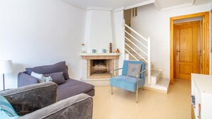 A living room with a sofa, armchair, and a fireplace. There is a staircase leading to another level. - Beach front home in Santa Pola (Santa Pola)