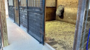 A stable with metal gates, hay on the floor, and a hay feeder on the wall. - Barndominium on the Bourbon Trail - Hot Tub and Horses!  Dog and Horse friendly! (Lawrenceburg)