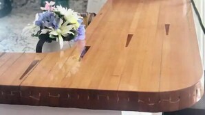 A wooden kitchen counter with a vase of flowers, wooden cabinets, a clock, and a vintage radio. - Barndominium on the Bourbon Trail - Hot Tub and Horses!  Dog and Horse friendly! (Lawrenceburg)