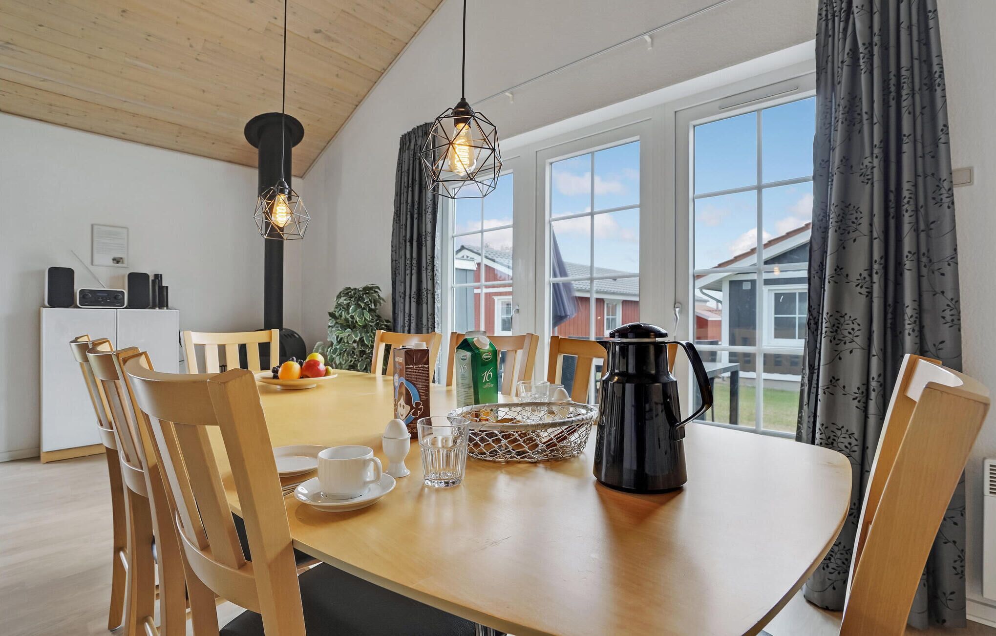 A dining area with a wooden table, chairs, a coffee maker, and a fruit bowl.