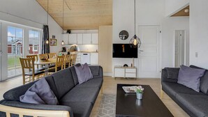Un soggiorno moderno con un divano grigio, un tavolino da caffè e un'area pranzo con sedie e tavolo in legno.