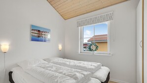 Una camera da letto con un letto, una finestra che si affaccia su delle case e un quadro appeso al muro.