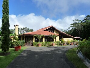 A two-story house with a red-tiled roof, a chimney, and a paved driveway leading to the entrance. - Luxury Private Villa Amazing Views Gated Paradise Starlink Hi-Speed Internet (Cayey)