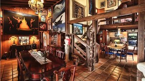 Ein geräumiger Essbereich mit einem großen Holztisch und Stühlen, einer Kristallleuchter und einer Treppe, die zu einer oberen Ebene führt.