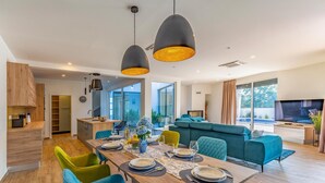 Un espace de vie moderne comprenant un coin repas, une cuisine et un coin salon avec un téléviseur.