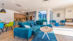 Un salon moderne avec un canapé de couleur turquoise, une table basse ronde et un coin repas comprenant une table et des chaises en bois.