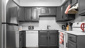 Une cuisine moderne avec des meubles gris, un lave-vaisselle, une cuisinière et un évier.