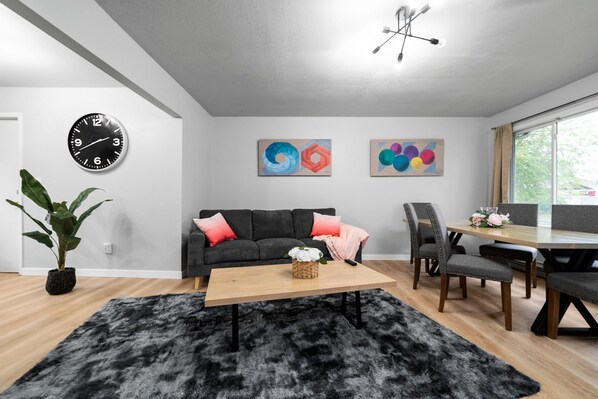 Een moderne woonkamer met een bank, salontafel en kunstwerk aan de muur.