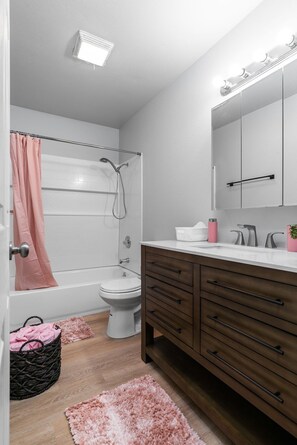 Een badkamer met een bad, toilet, wastafel en douche.