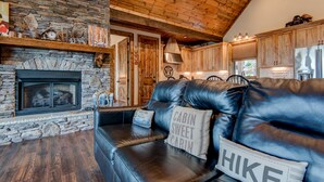 A cozy cabin interior with a stone fireplace, leather sofa, and wooden ceiling. - Lucky 7 at Eagles Nest: Long Range Views | Huge Deck | Firepit | Walk to Tennis! (Banner Elk)