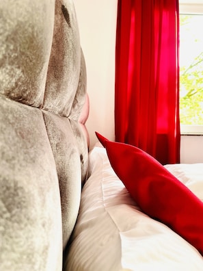 A close-up of a bed with a tufted headboard and a red pillow. - story Hostel Hamburg (Hamburg)