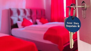 A hotel room with a bed, red curtains, and a key with a tag reading "Hotel Story Reeperbahn 66". - story Hostel Hamburg (Hamburg)