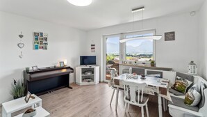 Un soggiorno moderno con un pianoforte, una TV e un'area pranzo con tavolo e sedie.