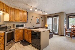 A compact kitchen with wooden cabinets, a microwave, a toaster, and a dishwasher.