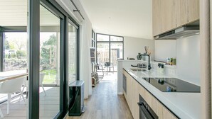 Eine moderne Küche mit großem Fenster, Schiebetüren und Blick auf den Garten.