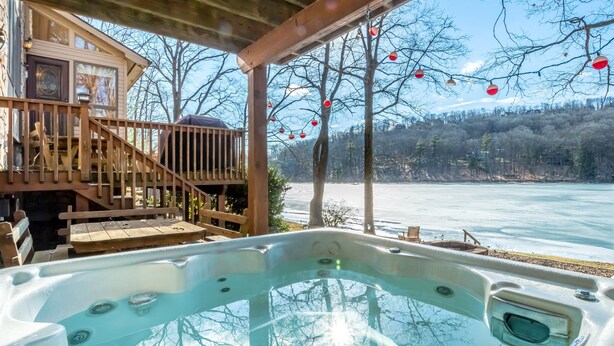 A hot tub with a wooden deck and a view of a frozen lake. - Gone Fish Inn by Taylor Made Deep Creek (McHenry)