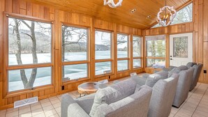A cozy room with large windows, a fireplace, and a seating area. - Gone Fish Inn by Taylor Made Deep Creek (McHenry)