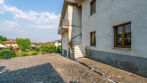 Ein zweistöckiges Gebäude mit einem gepflasterten Innenhof, einer Treppe und Blick auf die Umgebung.