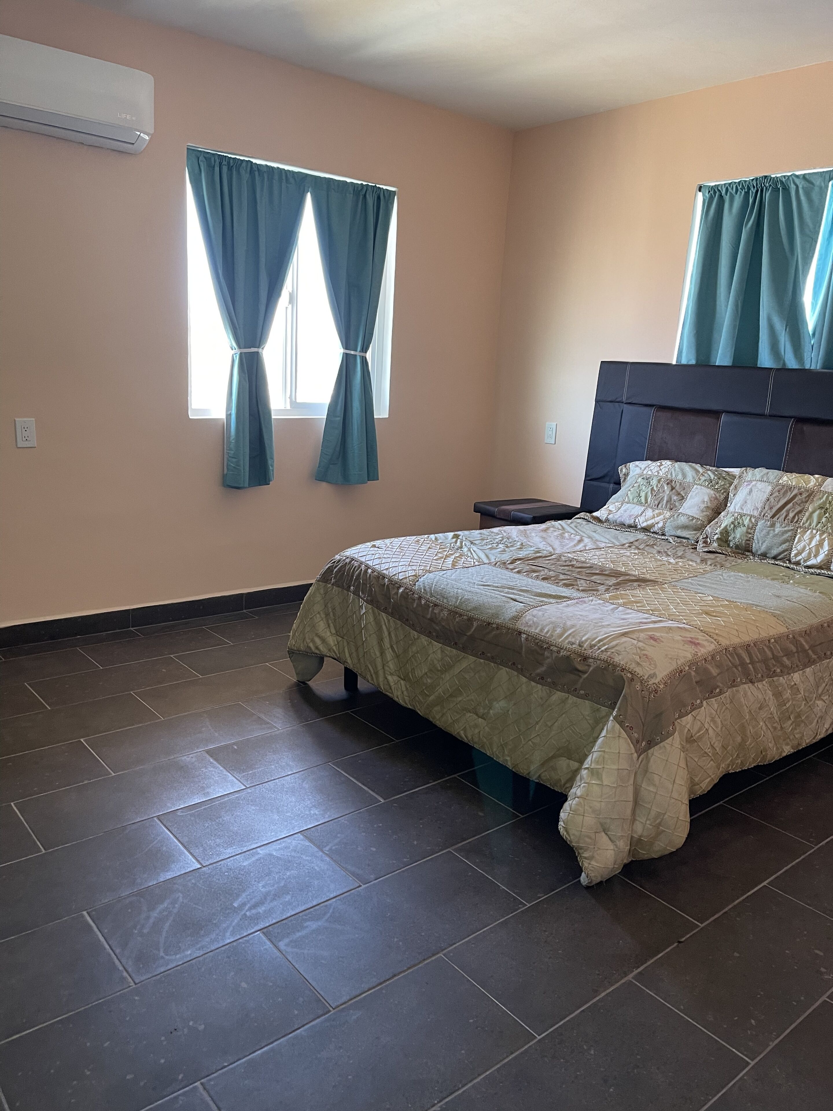 A bedroom with a bed, a nightstand, and a window with curtains.