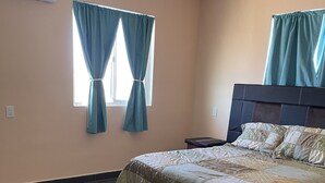 Een slaapkamer met een bed, een nachtkastje en een raam met gordijnen.