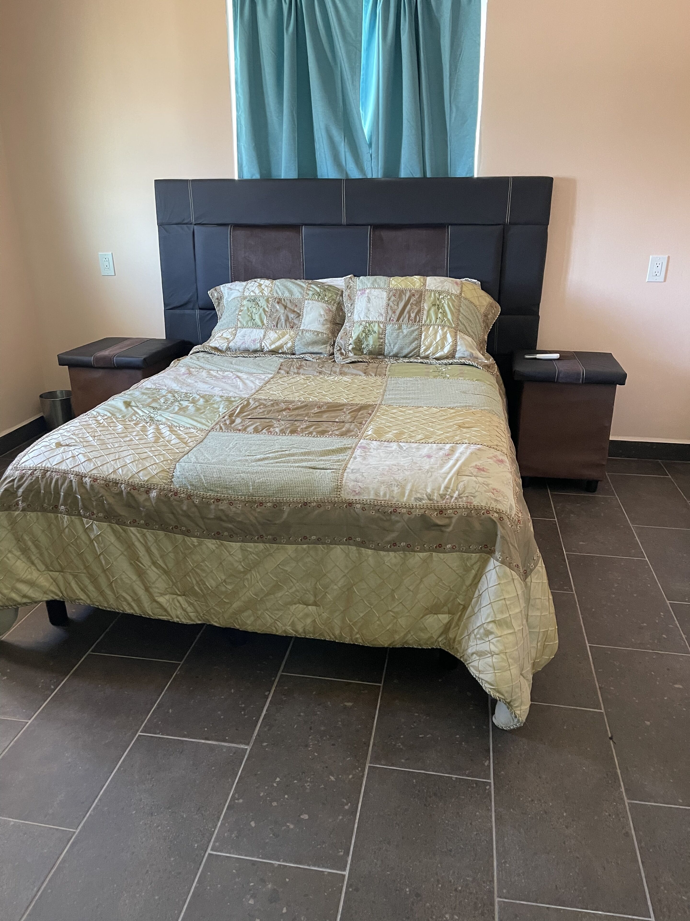 Un lit avec une couvre-lit matelassé, deux tables de chevet et une tête de lit.