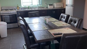Een kleine keuken met een eettafel, stoelen, een fornuis, een magnetron en een koelkast.
