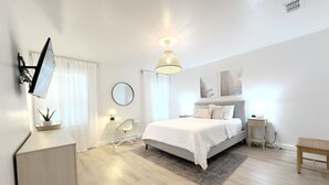 Ein modernes Schlafzimmer mit Bett, Nachttischen, Schreibtisch und Stuhl.