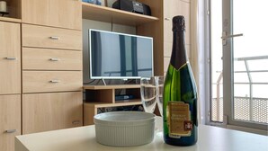 A room with a wooden cabinet, a television, a bottle of champagne, and a white bowl on a table. - Gorgeous apartment in Oostende (Oostende)